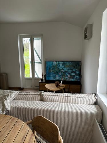 a living room with a couch and a flat screen tv at Le coin des hirondelles in Asfeld