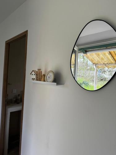 einen Spiegel an einer weißen Wand mit einem Fenster in der Unterkunft Le coin des hirondelles in Asfeld