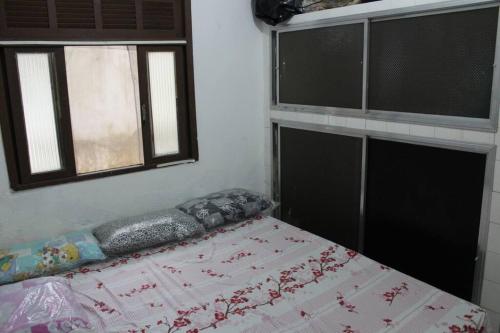 a bed in a room with two windows at Casa da Alvenaria- Praia de Mauá in Rio de Janeiro