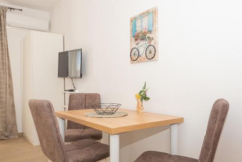 a dining room table with chairs and a tv at Apartments Lovrić in Vodice
