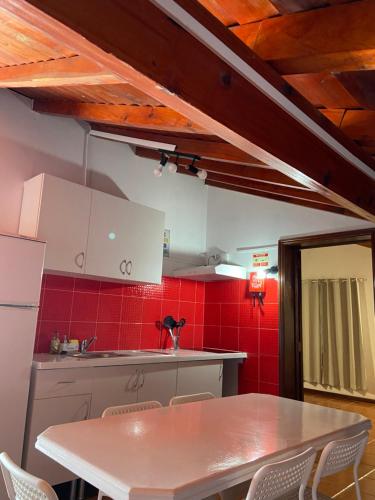 a kitchen with a table and some red tiles at Santo Cristo Loft in Lajes das Flores