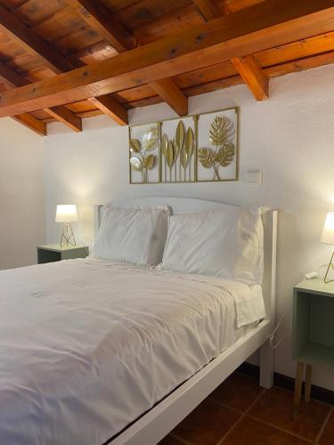 a bedroom with a bed with white sheets and two lamps at Santo Cristo Loft in Lajes das Flores