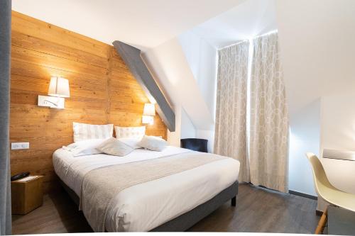 a bedroom with a large bed with a wooden wall at Hôtel des Princes, Chambéry Centre in Chambéry