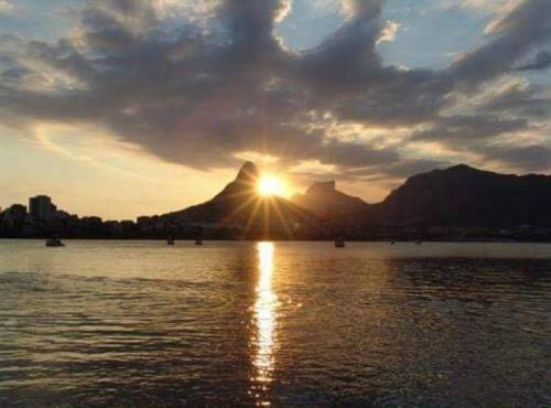 una puesta de sol sobre un cuerpo de agua con una montaña en Quarto super especial no Rio en Río de Janeiro
