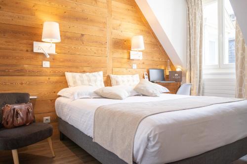 - une chambre avec un grand lit et un mur en bois dans l'établissement Hôtel des Princes, Chambéry Centre, à Chambéry