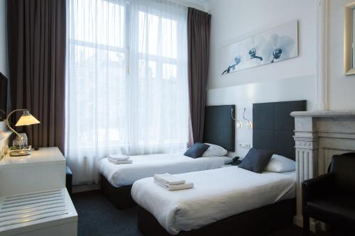 a hotel room with two beds and a window at Hotel Vossius Vondelpark in Amsterdam