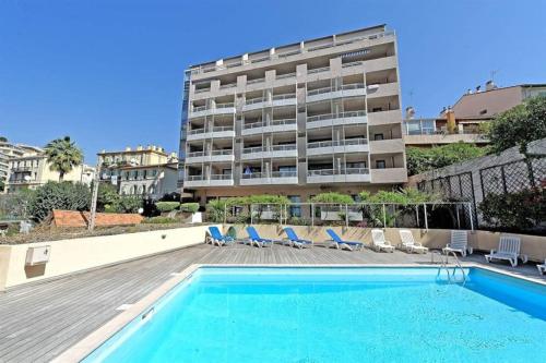 une piscine avec des chaises et un bâtiment dans l'établissement 2 pièces avec piscine, 150 m de la plage., à Cannes