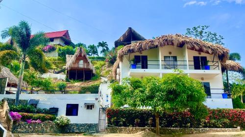 a white house with a thatch roof at Tayrona Angel Lodge in El Zaino