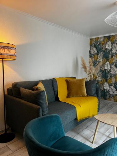 a living room with a couch with a yellow blanket at Chambres d'hôtes Le Maroni in Courseulles-sur-Mer
