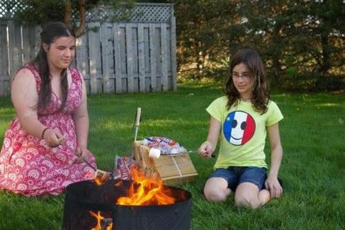 Pointe-du-Chêne的住宿－Vacation Village，两个女孩坐在火旁的草地上