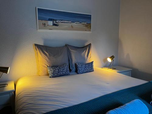a bedroom with a white bed with two pillows at Chambres d'hôtes Le Maroni in Courseulles-sur-Mer