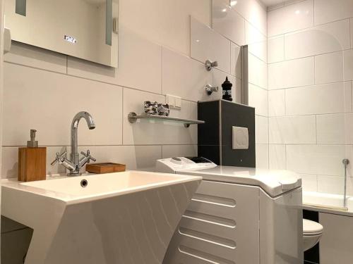 een witte badkamer met een wastafel en een toilet bij Retro & Vintage Apartment in Erkrath