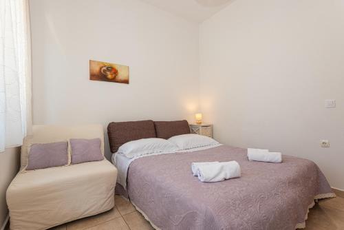 a bedroom with a bed and a chair in it at Apartments Lovrić in Vodice
