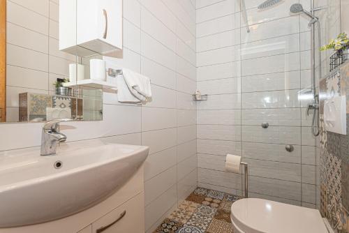 a white bathroom with a sink and a shower at Apartments Lovrić in Vodice