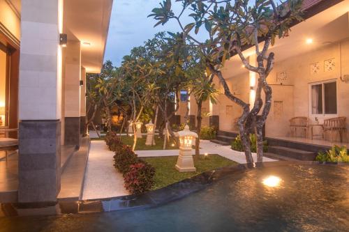 a building with a courtyard with trees and plants at The Cozy Haven Sanur in Sanur