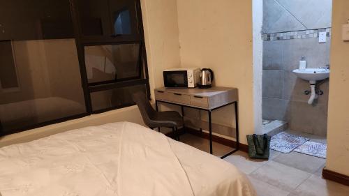 a bedroom with a bed and a sink and a microwave at Lerato's in Vanderbijlpark
