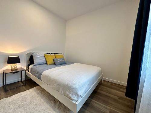 a white bedroom with a bed and a night stand at Coin paisible au large de Québec in Quebec City
