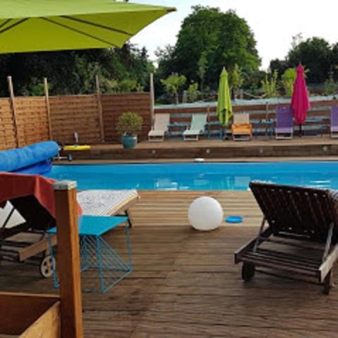 - une piscine bordée de chaises longues et de parasols dans l'établissement chambre zen, à Condé-sur-Noireau