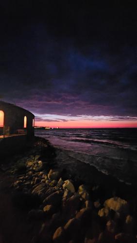a building on a beach with the ocean at night at Mary J Apartment in Trapani