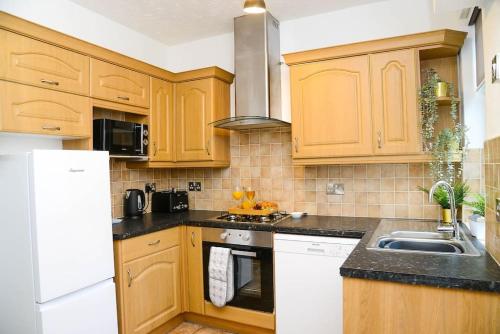 una cocina con armarios de madera y fregadero en Delightful 2 bed town centre house, sleeps 4, en Barnsley