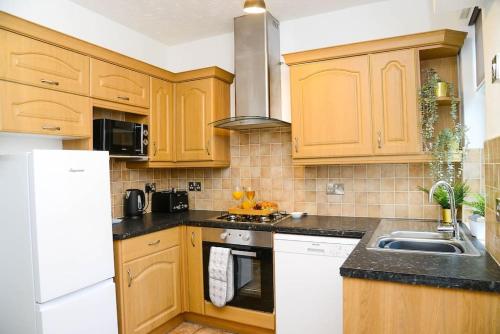 a kitchen with wooden cabinets and a sink at Delightful 2 bed town centre house, sleeps 4 in Barnsley