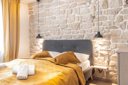 a bedroom with a large bed with a stone wall at L&B amphitheater apartments in Pula