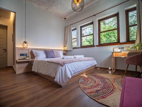 a bedroom with a bed and a desk and windows at Αρχοντικό Πορταριάς in Portariá