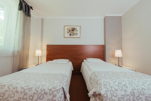 two beds in a hotel room with white sheets at Hotel Pod Sosnami in Osieck