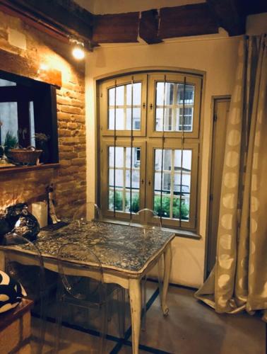 une salle à manger avec une table et deux fenêtres dans l'établissement Triplex avec terrasse, aux pieds de la cathédrale, 5 personnes, à Strasbourg