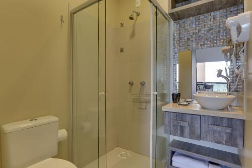 a bathroom with a shower and a toilet and a sink at Flat Pietra in Florianópolis