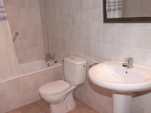 La salle de bains blanche est pourvue de toilettes et d'un lavabo. dans l'établissement Apartamentos Cal Ratero, à Maçanet de Cabrenys
