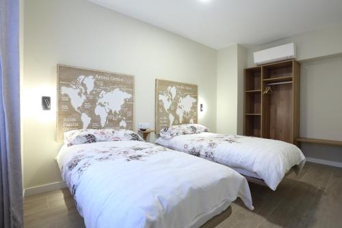 two beds in a bedroom with white sheets and flowers at Pensión Casa Carmen in Estella