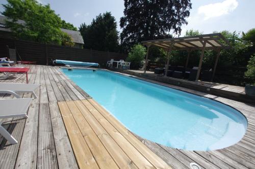 a large blue swimming pool with a wooden deck at Chambre liberté in Condé-sur-Noireau