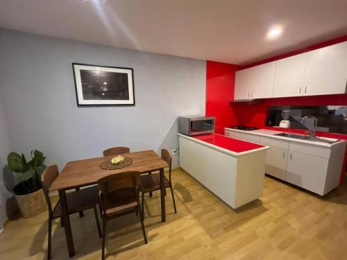 a kitchen with a table and a kitchen with red walls at Oaxaca departamento azul in Oaxaca City