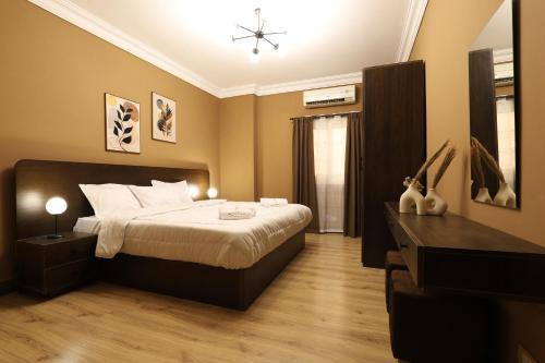 a bedroom with a large bed and a dresser in it at Signature Stays: Modern Chic Apt in Cairo