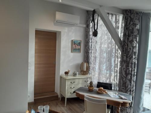 a room with a table and a dresser and a window at Un petit coin de paradis à Haute Jarrie in Jarrie
