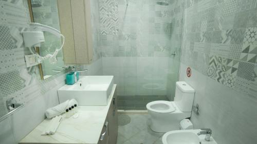 a white bathroom with a toilet and a sink at Gent's Inn in Durrës