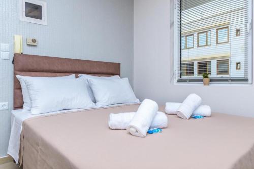 Cama blanca con almohadas blancas y ventana en Sergios Apartments 4, en Alexandroupoli