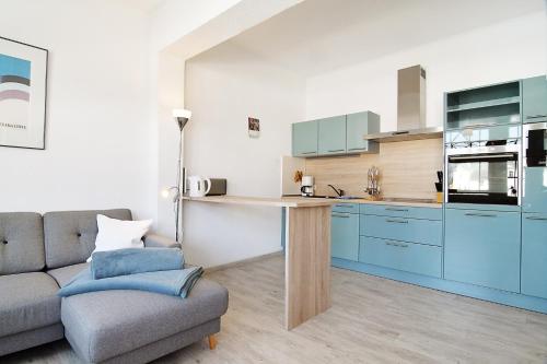 ein Wohnzimmer mit einem Sofa und eine Küche mit blauen Schränken in der Unterkunft Hamburg App. 06 in Ahlbeck