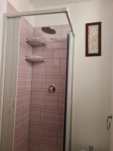 y baño con ducha y azulejos de color rosa. en Casetta Verde, en Tricarico