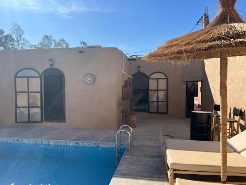 a house with a swimming pool and an umbrella at Villa C à 5km du centre in Marrakesh