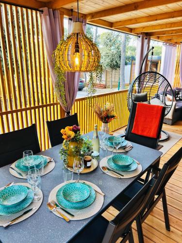 - une table à manger avec des assiettes et des verres sur une terrasse couverte dans l'établissement Mobile Home ORANGE Camp Soline, à Biograd na Moru