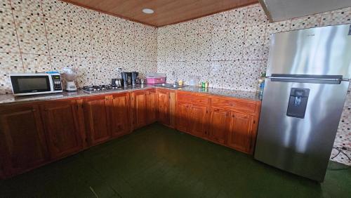 a kitchen with wooden cabinets and a stainless steel refrigerator at Bastimentos Hill Guest House in Bocas del Toro