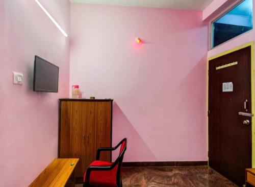 a red chair in a room with a pink wall at Gautam Villa Home Stay Varanasi in Varanasi