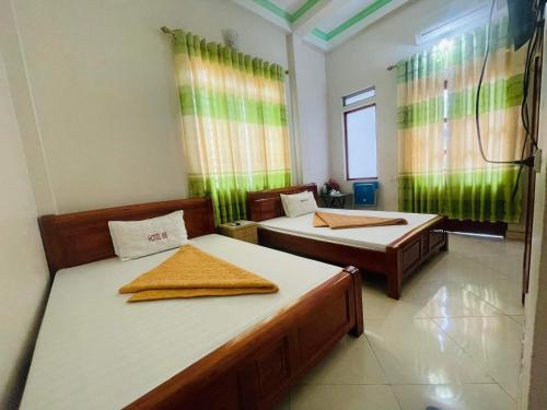 two beds in a room with green curtains at HOTEL 88 in Yên Minh