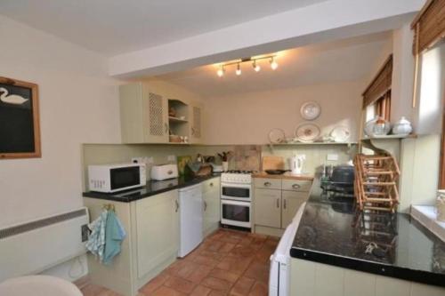 a large kitchen with white cabinets and appliances at Lime Cottage in Minehead