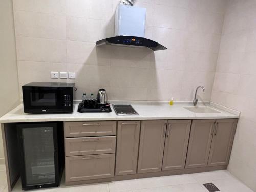 een keuken met een wastafel, een magnetron en een fornuis bij لافانتا للشقق المخدومه - LAVANTA Hotel in Al Khobar