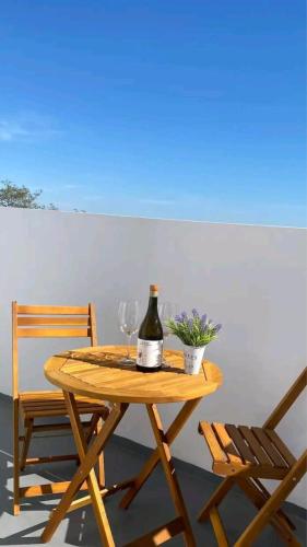 a wooden table with a bottle of wine and two glasses at Lugar do Sonho Apartamento in Cercal