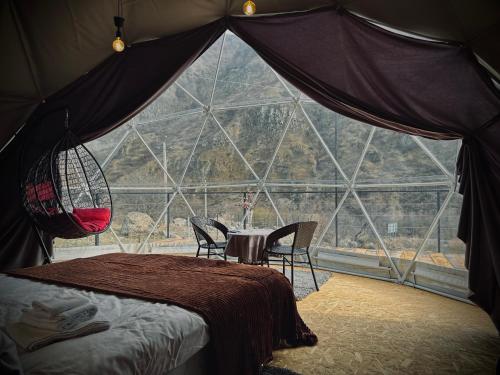 Zelt mit einem Tisch und Stühlen vor einem Fenster in der Unterkunft Vardzia Glamping in Wardsia