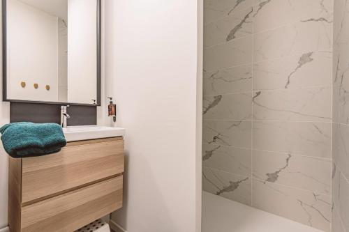 une salle de bain avec un lavabo et une douche dans l'établissement HENRI au pied de la cathédrale., à Reims